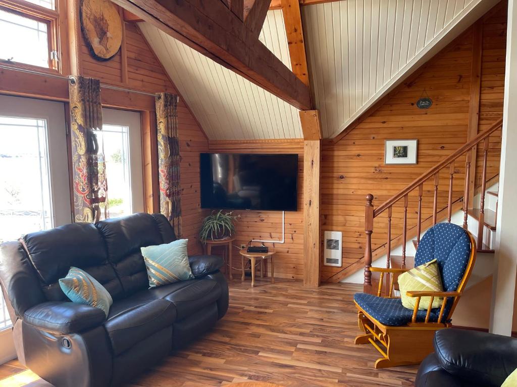 Una sala de estar con un sofá y un televisor. en Beach & Breeze Cottages, en Stanley Bridge