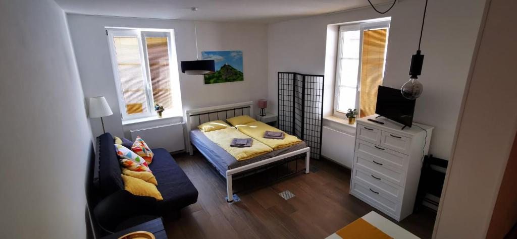 Apartmán Augustin Jičín في جيسين: غرفة نوم صغيرة مع سرير وأريكة