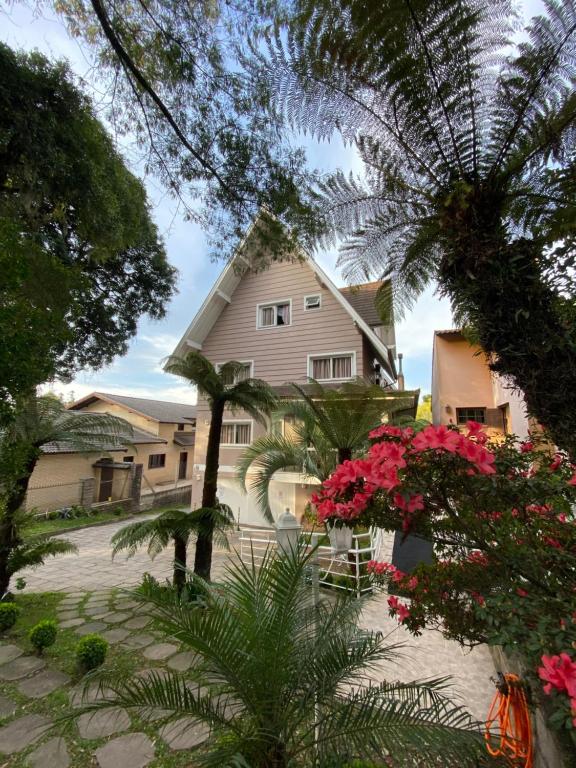 ein Haus mit Palmen und Blumen davor in der Unterkunft Pousada Vovô Nino in Gramado