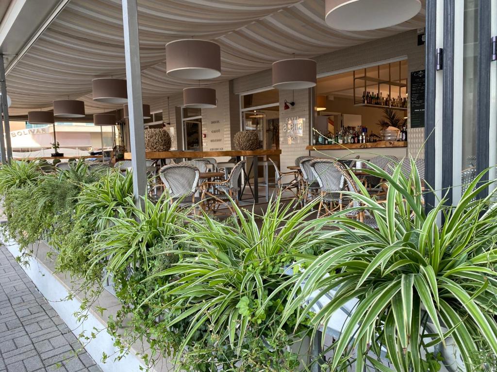 un restaurante con mesas, sillas y plantas en Hotel Arena, en Lido di Jesolo