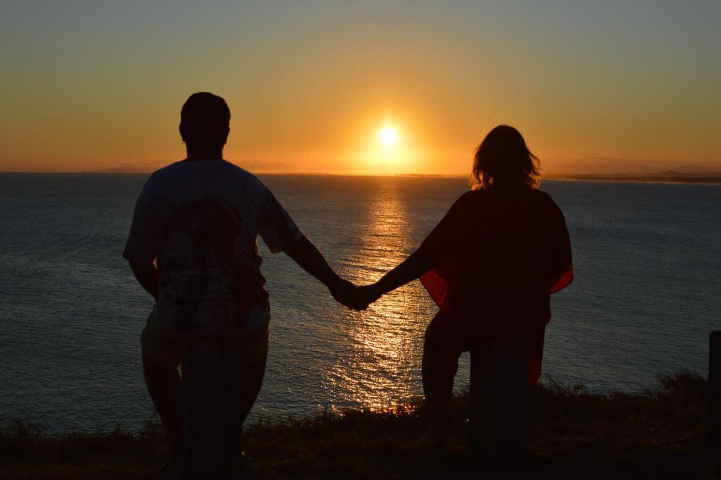 een paar handen vasthouden terwijl ze de zonsondergang bekijken bij Cantinho da Praia in Arraial do Cabo