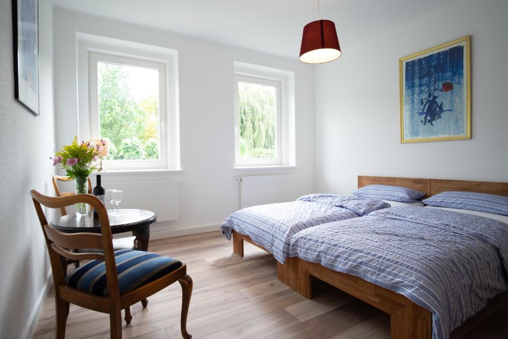 a bedroom with a bed and a table and two windows at Altstadt Apartment in Goslar