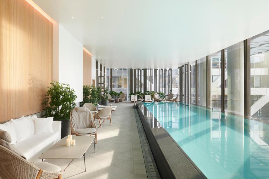 a pool in the middle of a building with chairs at Pan Pacific London in London