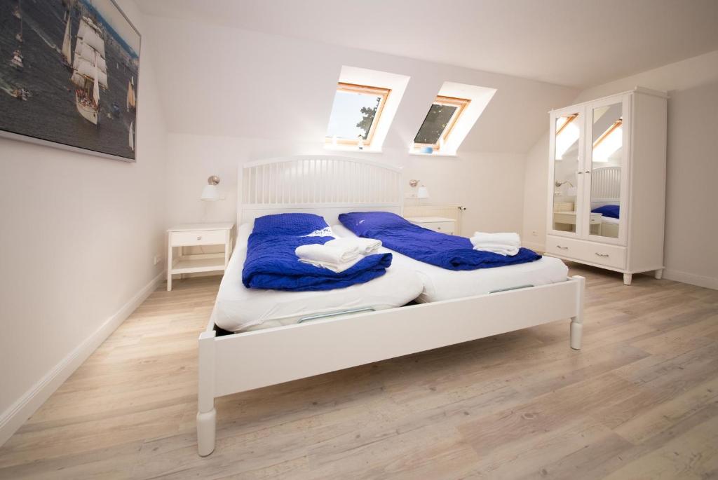 a bedroom with a white bed with blue blankets at Schleiblick App 18 in Rabenkirchen-Faulück