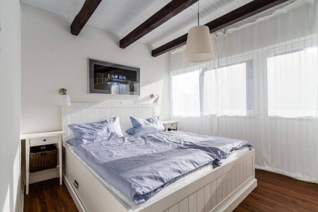 a white bedroom with a bed with blue sheets at Kleines Sommerhaus Schröder - Im Winkel 1b in Dahme
