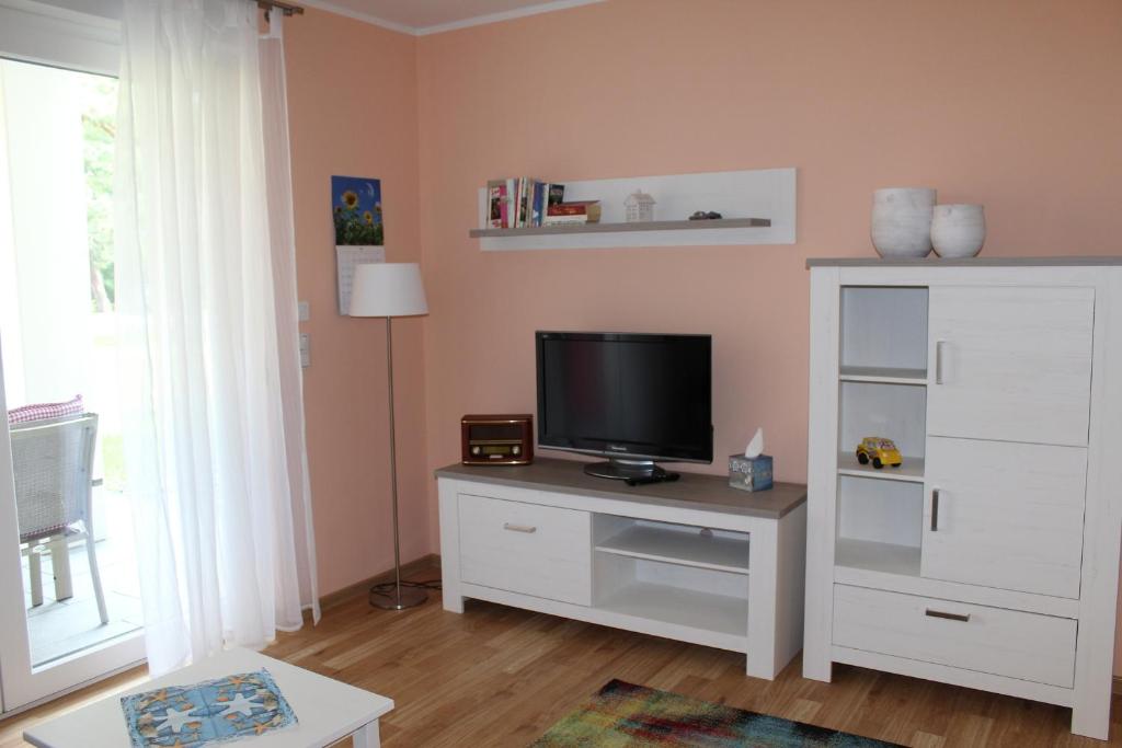 ein Wohnzimmer mit einem TV auf einem Stand mit einem Tisch in der Unterkunft Lachmöwe App 35 in Dierhagen