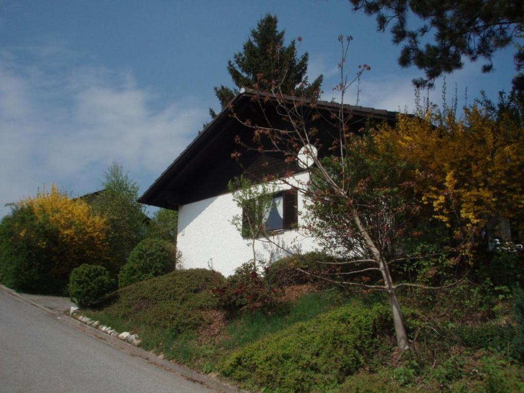 ein kleines weißes Haus auf einem Hügel neben einer Straße in der Unterkunft Ferienhaus Waldschrat - Komplettpreis in Zandt