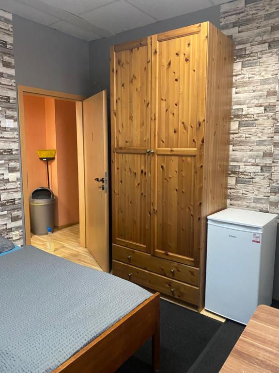 a bedroom with a refrigerator and a wooden cabinet at Hipokratios 1 in Fürth