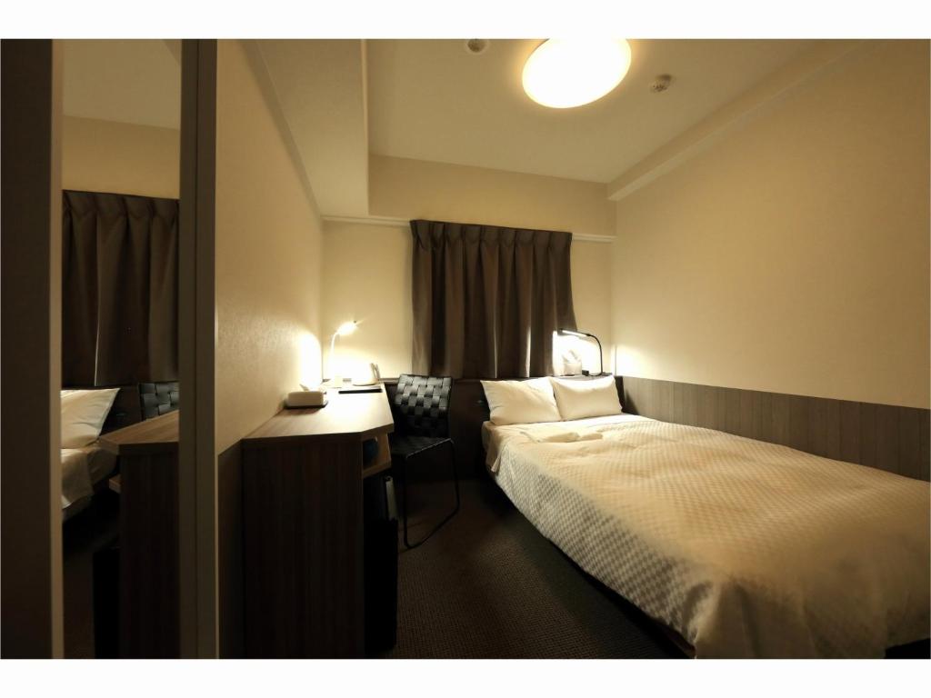 a hotel room with a bed and a desk at Sendai Business Hotel Ekimae - Vacation STAY 71918v in Sendai