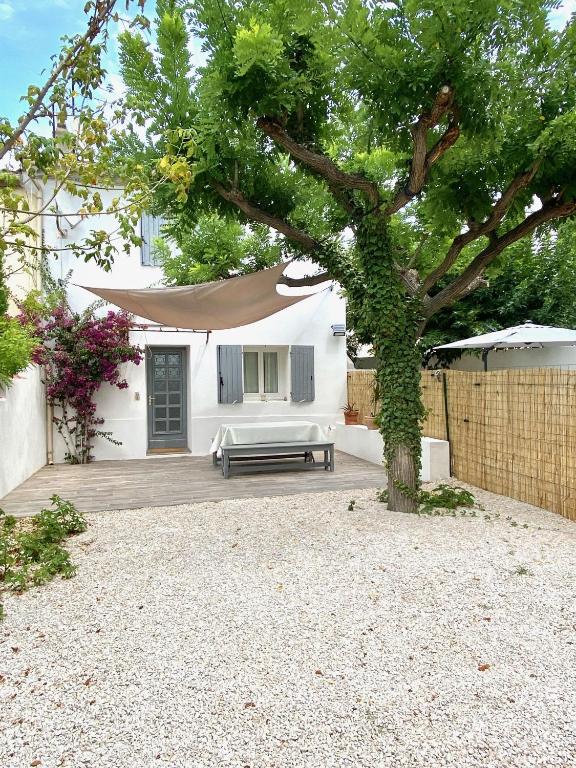 une maison blanche avec un arbre et un banc dans l'établissement Il y a le Soleil, la Campagne et la Mer …1, à Martigues