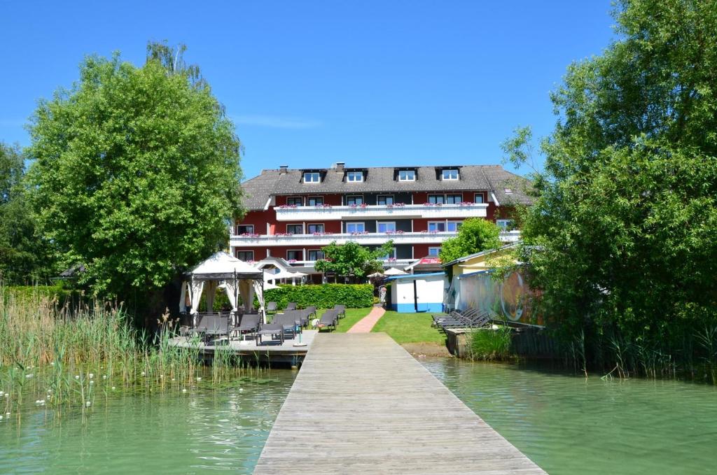 ein Gebäude an der Flussseite mit einem Dock in der Unterkunft Hotel Silvia in Sankt Kanzian am Klopeiner See