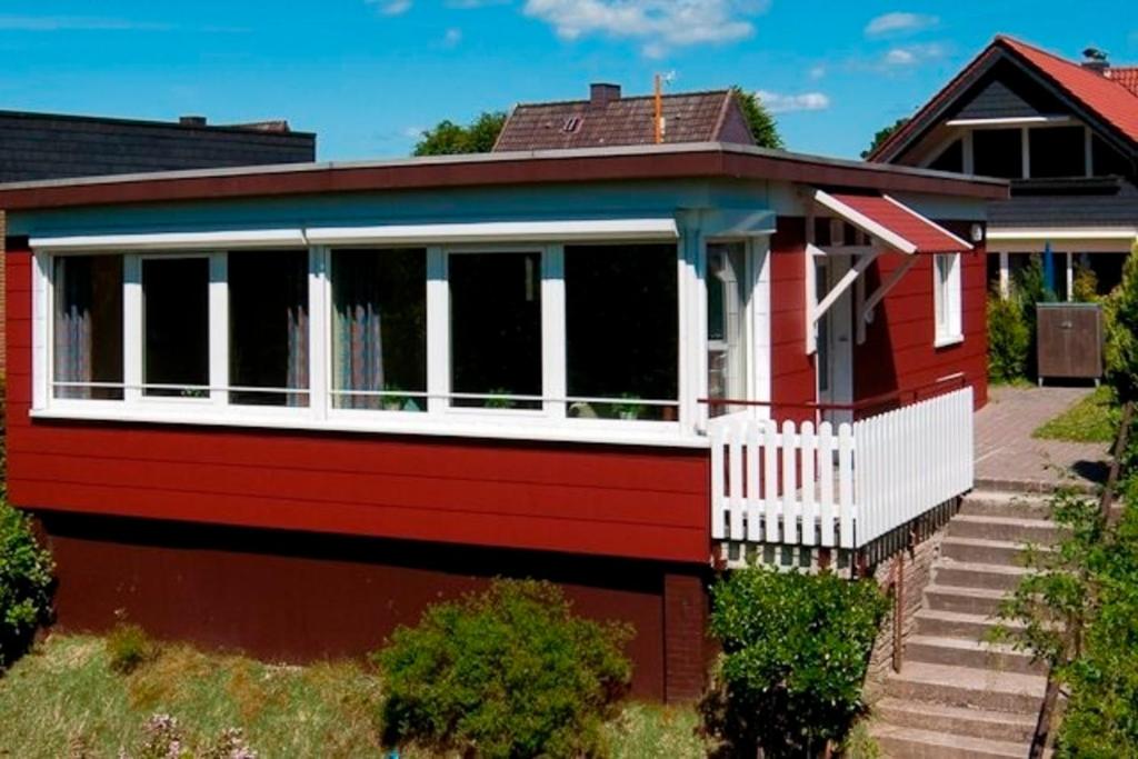 ein rotes Haus mit einem weißen Zaun in der Unterkunft Ferienhaus Dittrich in Eckernförde