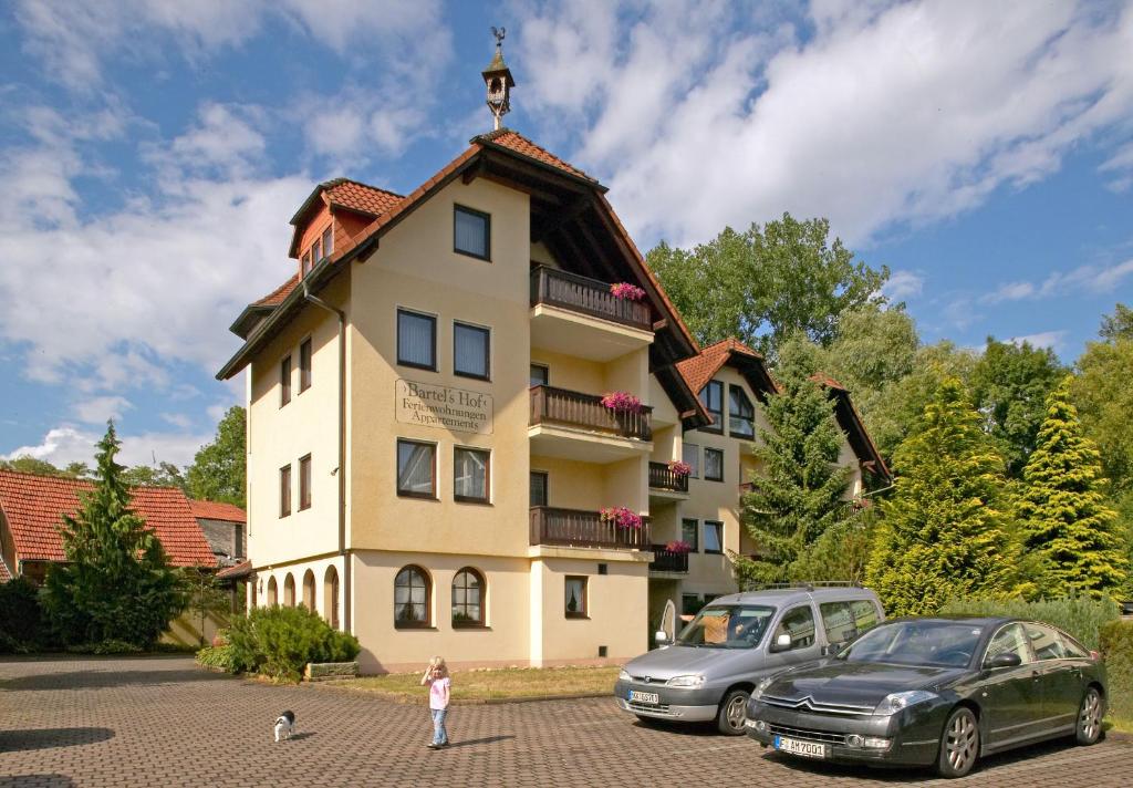 ein Gebäude mit zwei davor geparkt in der Unterkunft Bartelshof Appartementhaus in Bad Soden-Salmünster