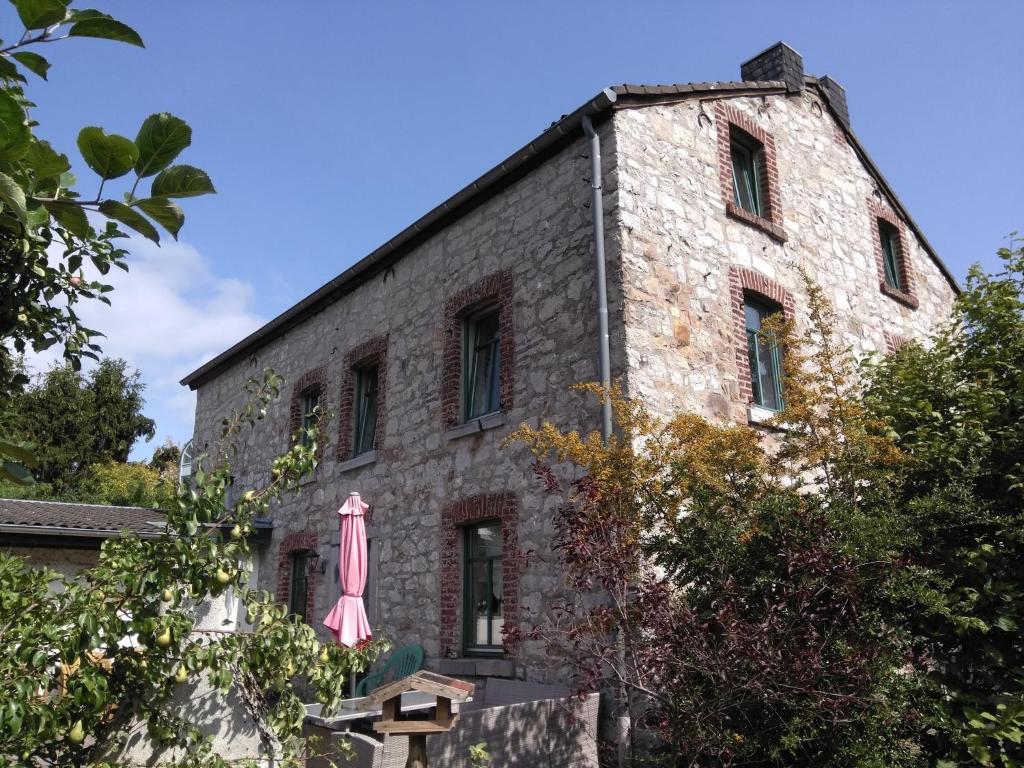 ein altes Steingebäude mit einem rosa Regenschirm draußen in der Unterkunft Ferienhaus Bettina in Stolberg