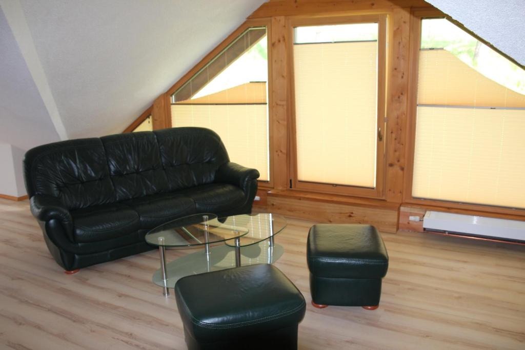 sala de estar con sofá de cuero negro y taburete en Ferienwohnung mit Balkon, en Sehmatal