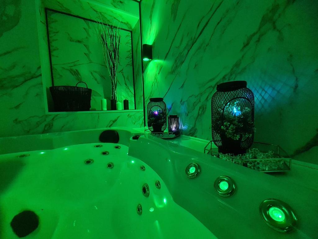 a green bathroom with a tub and a mirror at Luxury 9ine THE EXCLUSIVE JACUZZI APARTMENT in Birmingham