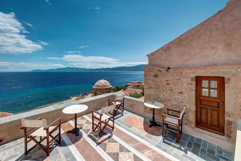 un patio con mesas y sillas con vistas al océano en Malvasia Traditional Hotel en Monemvasía