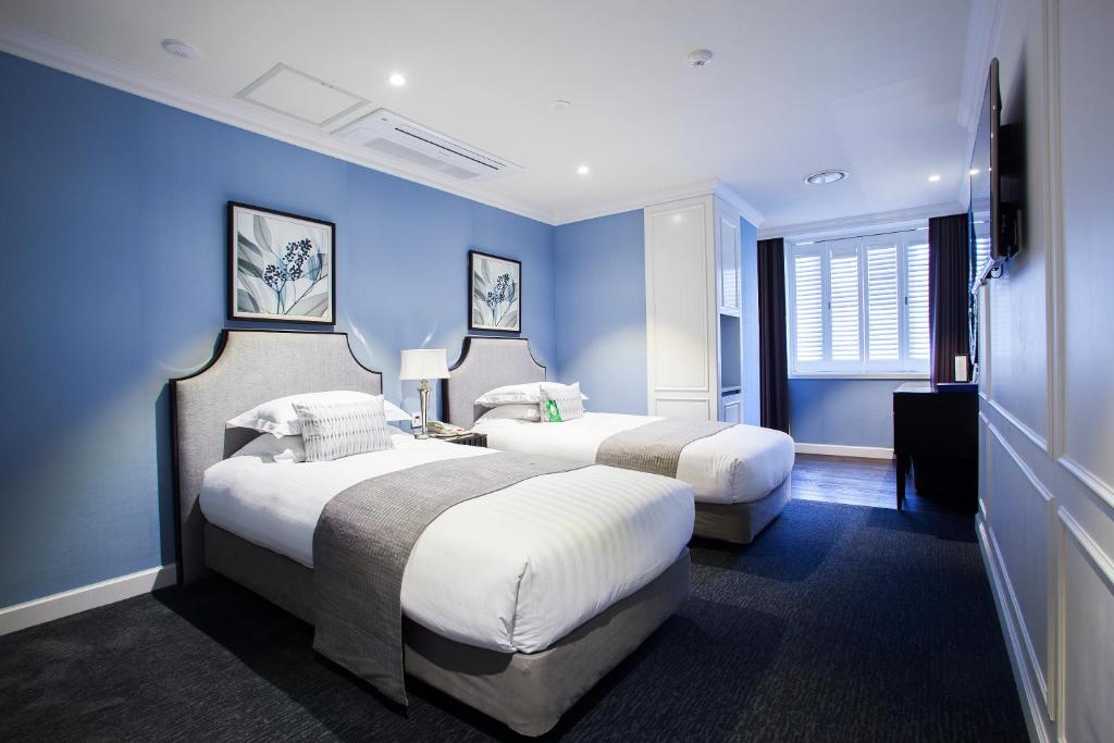 首爾的住宿－明洞大酒店，两张位于酒店客房的床,拥有蓝色的墙壁
