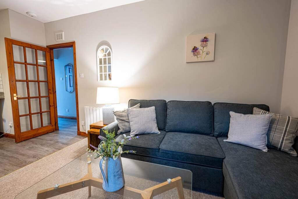 a living room with a blue couch and a table at Cozy Newly Renovated Town Centre Apartment in Aberfeldy
