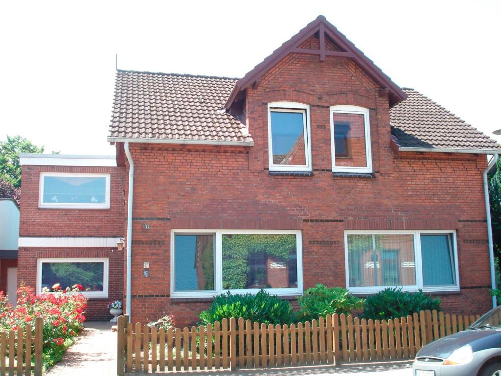 ein rotes Backsteinhaus mit einem Holzzaun in der Unterkunft Ferienwohnung Riek in Büdelsdorf