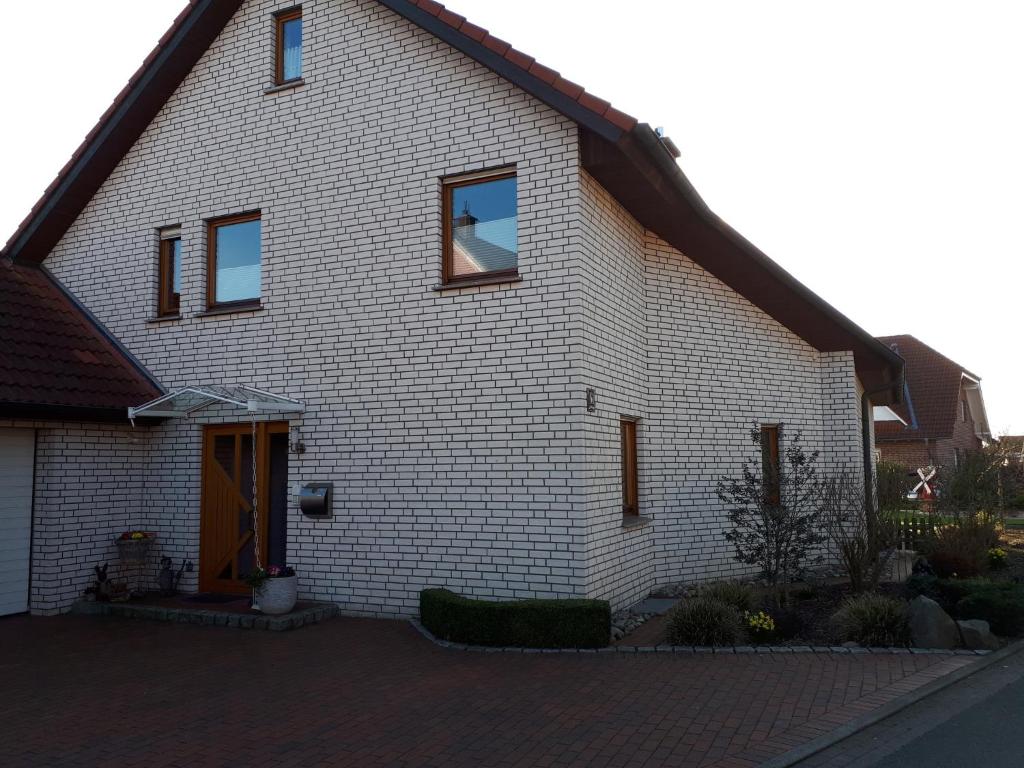 uma casa de tijolos brancos com uma porta castanha em Ferienwohnung-Lilienweg em Hilter