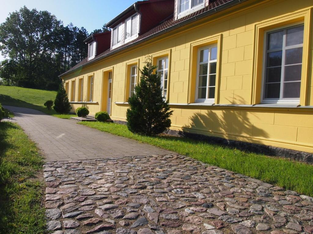 uma casa amarela com uma estrada de paralelepípedos à sua frente em Gut Rattelvitz, Parterre B em Gingst