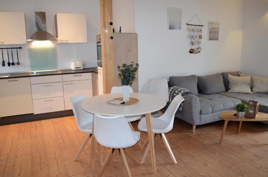 una cucina e un soggiorno con tavolo e sedie di Maritime Ferienwohnung auf Gut Bennewohld KP a Heide