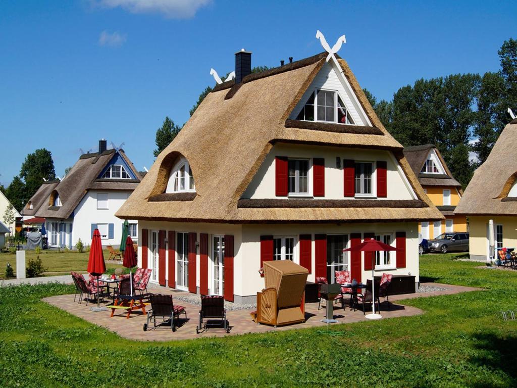 a house with a thatched roof with tables and chairs at Villa Harmony in Glowe