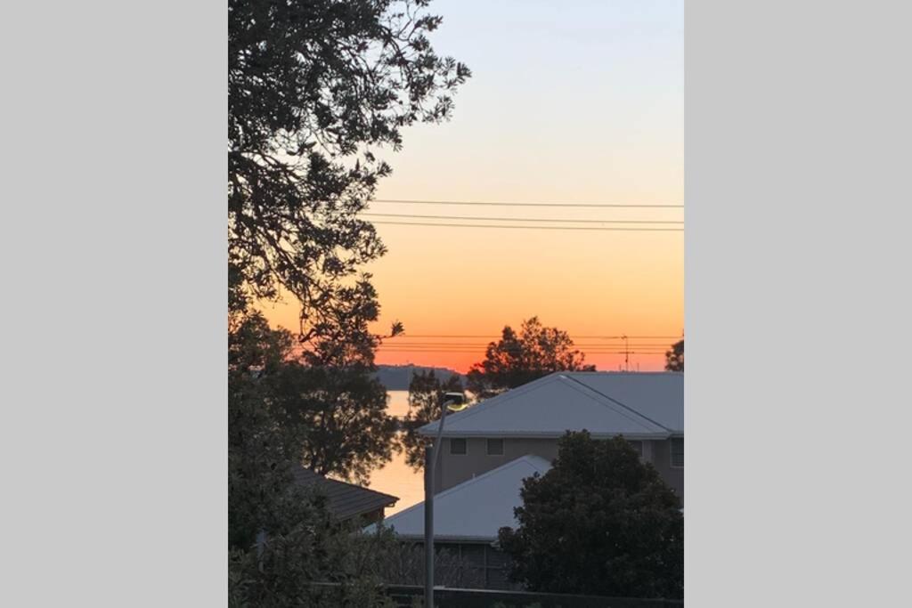 Blick auf den Sonnenuntergang vom Fenster eines Hauses in der Unterkunft Corlette Shores. Dreamy Beachside Holiday Home. in Corlette