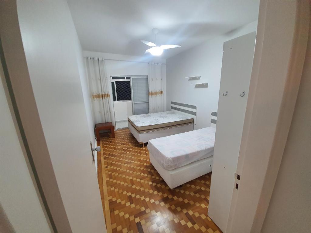 um pequeno quarto com 2 camas e um tecto em Apto a 250m da praia Enseada no Guarujá