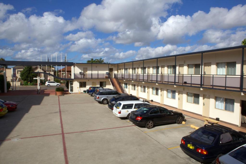 a group of cars parked in a parking lot in front of a building at Westside Motor Inn in Sydney