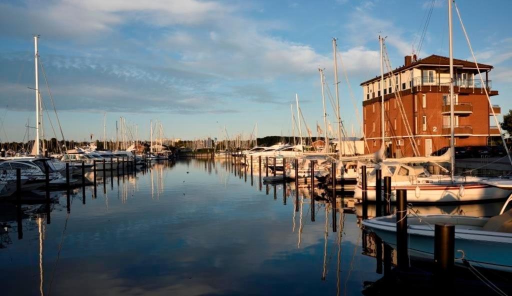 un groupe de bateaux amarrés dans un port de plaisance comportant un bâtiment dans l'établissement ancora Marina Haus 2 Penthouse, à Neustadt in Holstein