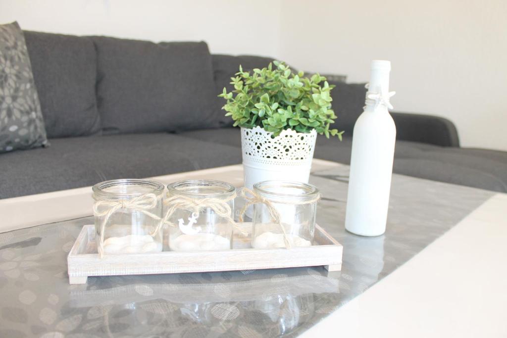 una mesa con tarros de cristal, una planta y una botella en Appartement Steffens - "Brookgang - Nr 2", en Grömitz