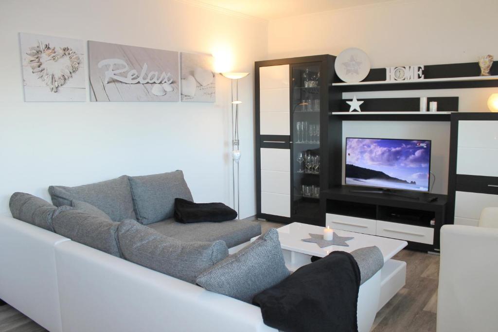 een woonkamer met een witte bank en een tv bij "Cala Grömitz - Haus Tanneck" in Grömitz