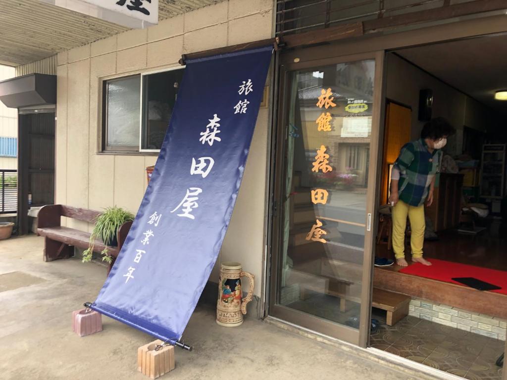 a building with a banner with asian writing on it at 竜ケ崎駅そばの森田屋旅館 in Ryūgasaki