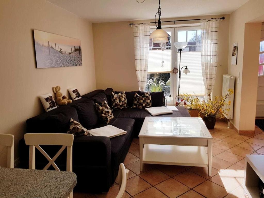 a living room with a black couch and a table at FeWo Lena in Hanerau-Hademarschen