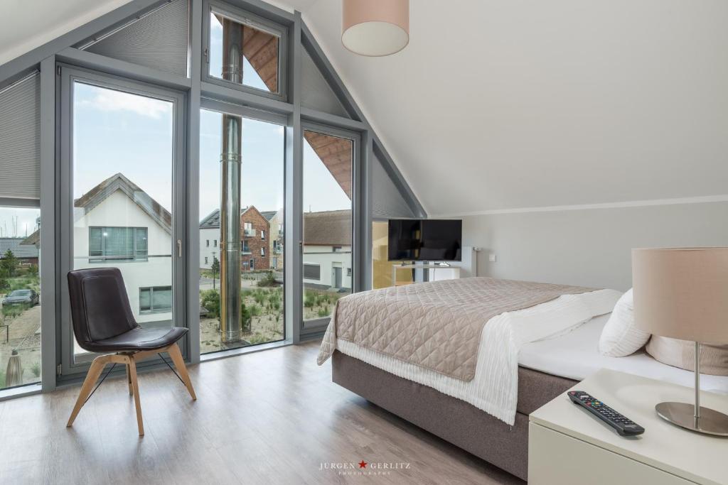 una camera con letto, sedia e finestre di Ostsee - Reetdachhaus Nr 7 "Haddock" im Strand Resort a Heiligenhafen