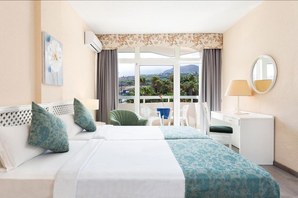 プエルト・デ・ラ・クルスにあるApartment 204 im Precise Resort Tenerifeの大きなベッドと窓が備わるホテルルームです。
