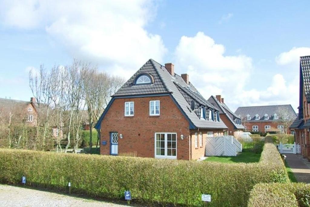a red brick house with a black roof at Wohnen auf'm Lande HT 6 in Oldsum