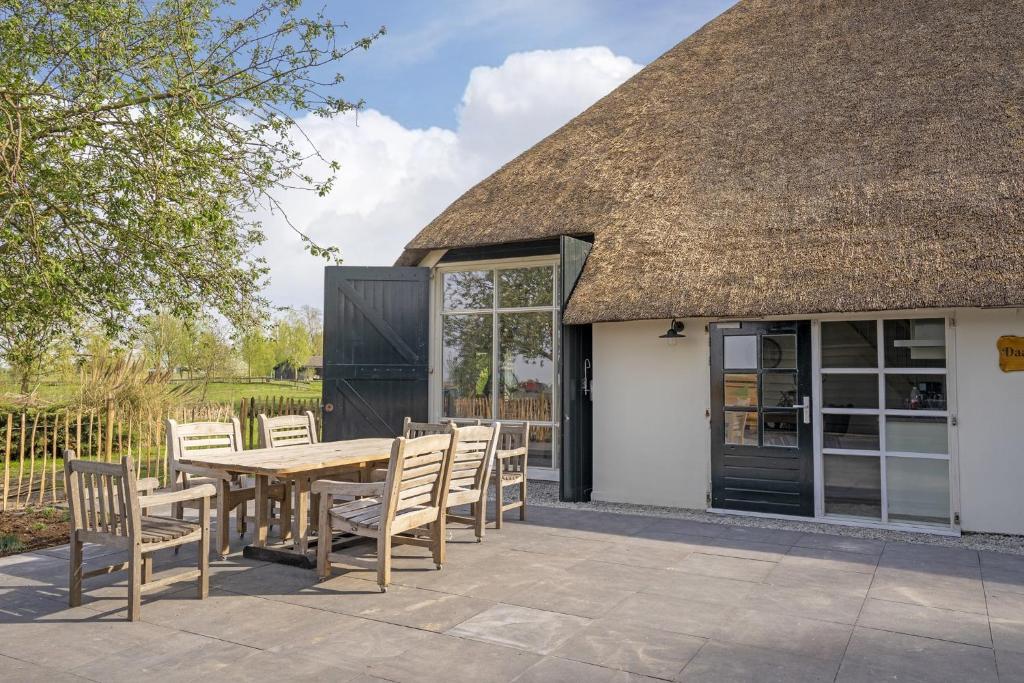 a thatch roofed patio with a wooden table and chairs at Daaldersplek Bantega in Bantega