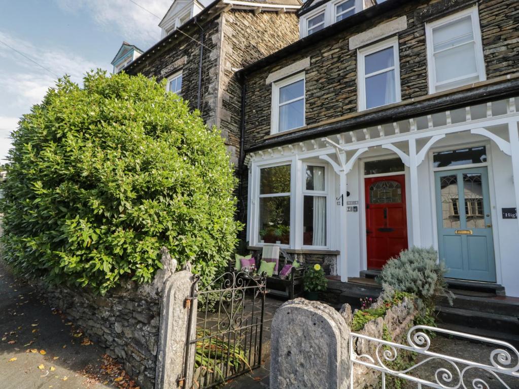 a brick house with a red door and a bush at Gillercombe in Bowness-on-Windermere