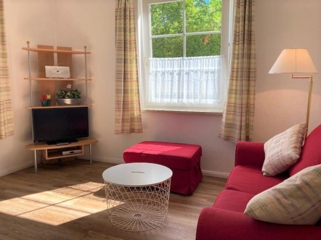 a living room with a red couch and a window at Ferienwohnung 4, EG, Hof zur Sonnenseite Fehmarn in Fehmarn