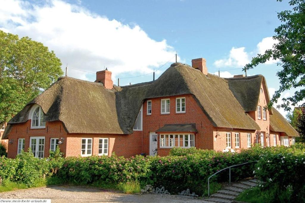 a large red brick house with a thatched roof at Pastoratshof - Whg8 in Wrixum