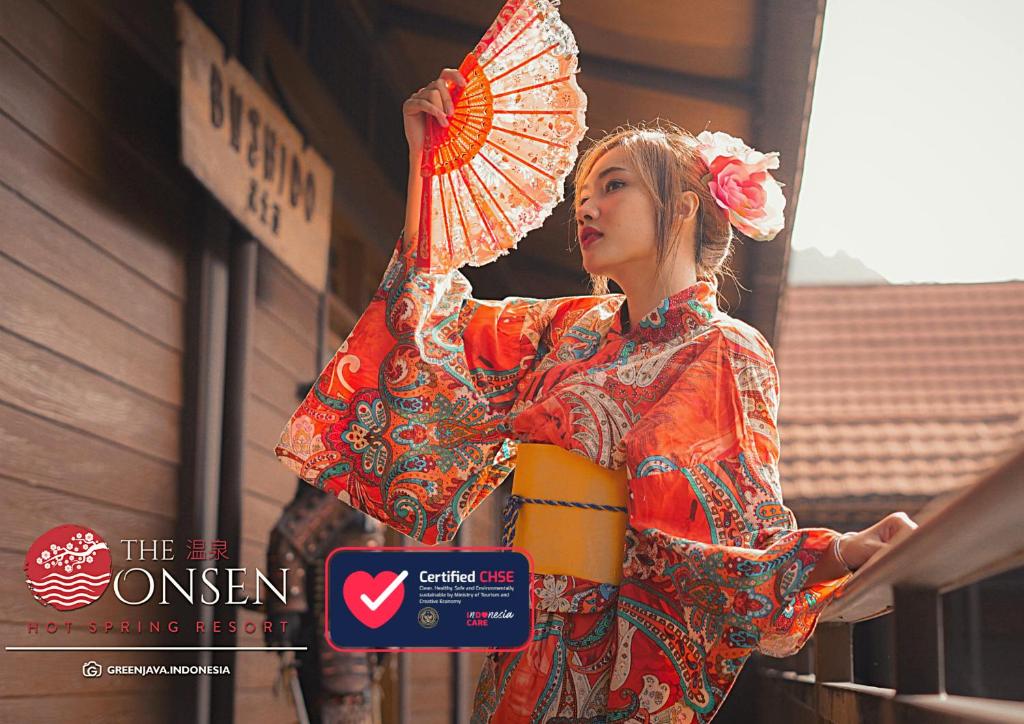 una mujer en un kimono sosteniendo un paraguas en The Onsen Hot Spring Resort, en Batu
