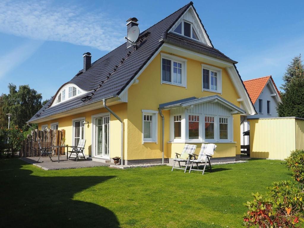 uma casa amarela com cadeiras no quintal em Grüner Winkel 32a em Zingst