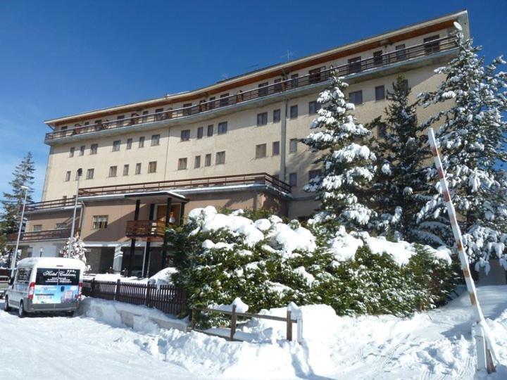 un autobus parcheggiato di fronte a un edificio ricoperto di neve di Hotel Caldora a Rocca di Mezzo