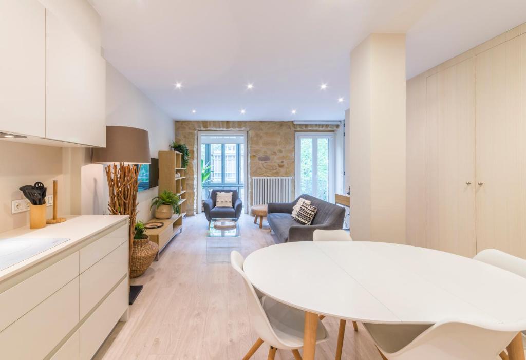 een keuken en een woonkamer met een witte tafel en stoelen bij Apartamentos Bellas Artes in San Sebastian