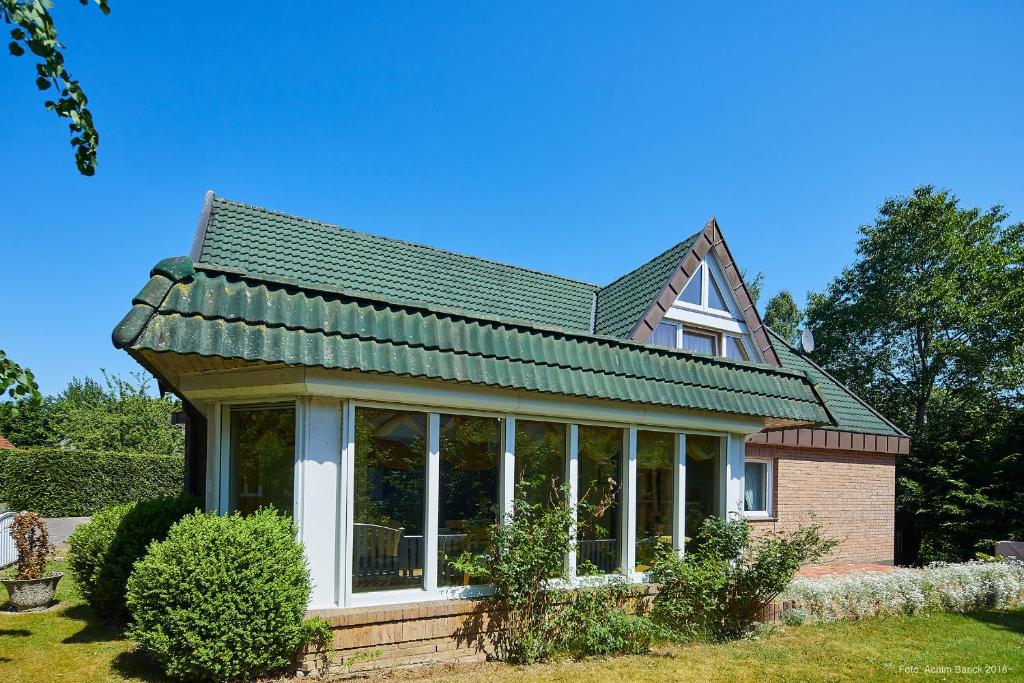 a house with a conservatory with a green roof at Doppelzimmer mit kleiner Pantryküche Gästehaus Unter den Linden in Mühbrook