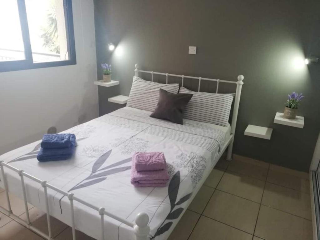um quarto com uma cama branca e toalhas em Cozy 1 bedroom apartment close to the beach em Pafos