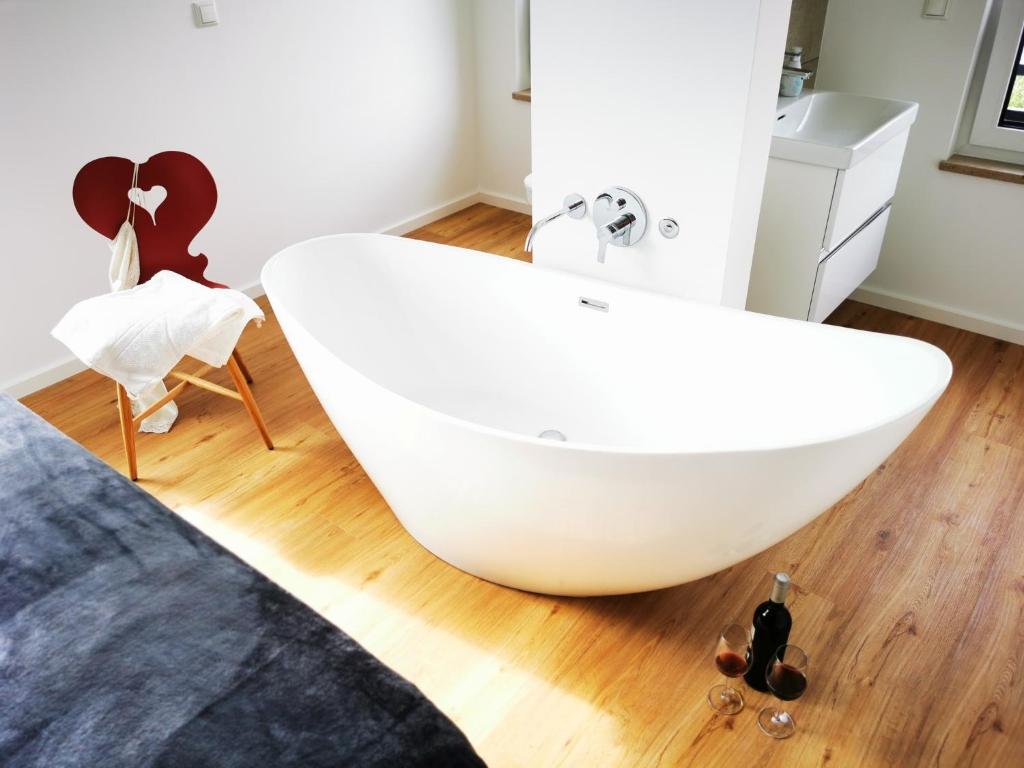 een badkamer met een wit bad en een houten vloer bij Chalethaus-Chiemsee - 120qm Panorama-Chaletwohnung am Chiemsee - Neubau in Prien am Chiemsee